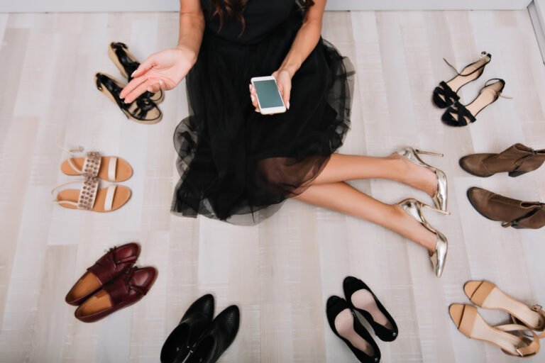 Woman sitting on floor surrounded a lot of shoes